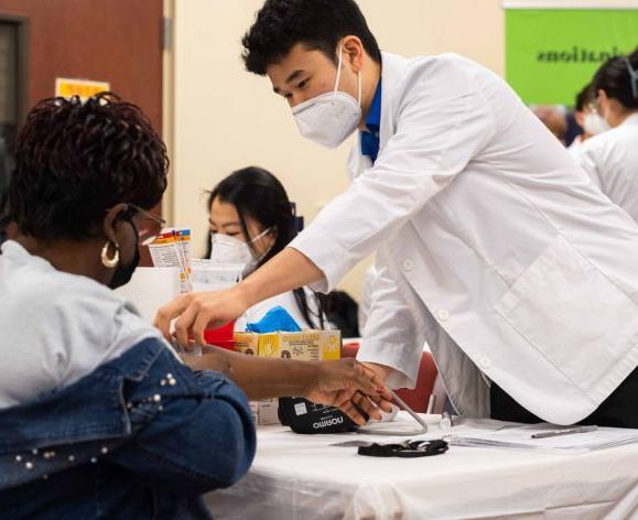 药店 student with community members at health care outreach clinic